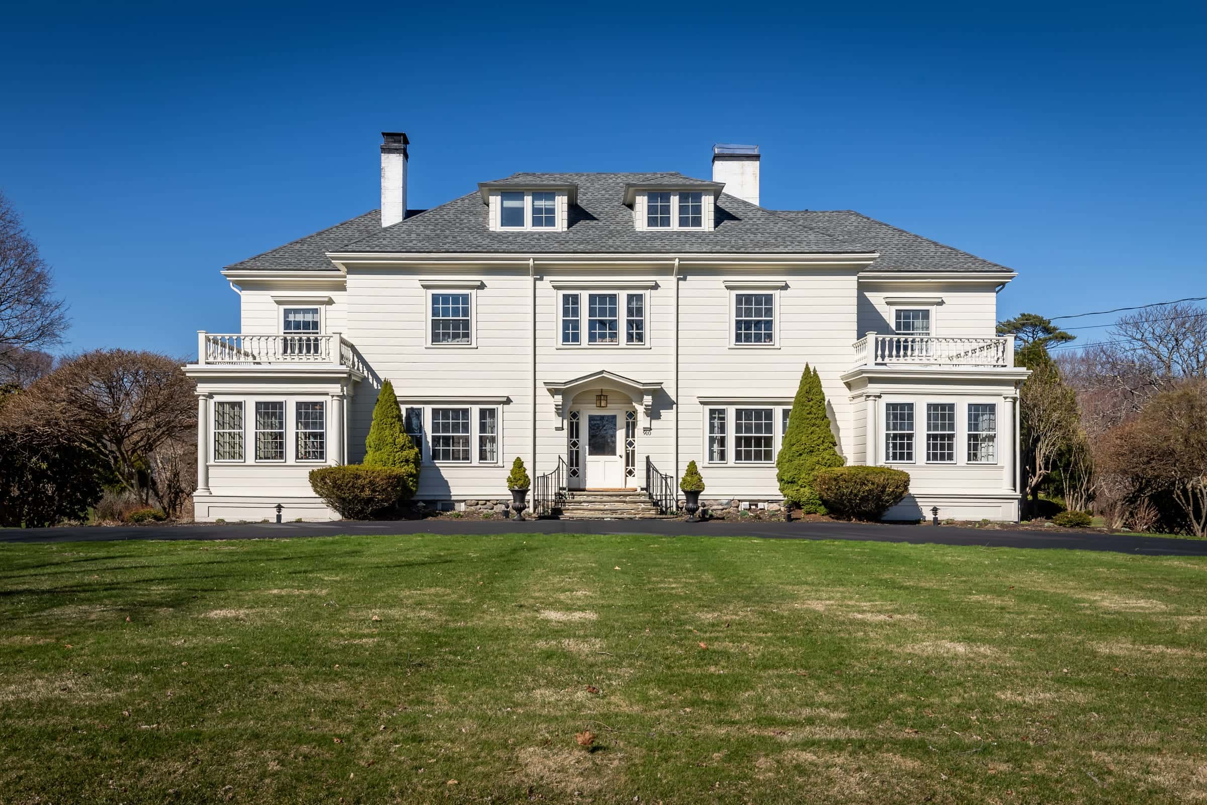 Front exterior photo of a classic white colonial home in Rye Beach, New Hampshire under a blue sky